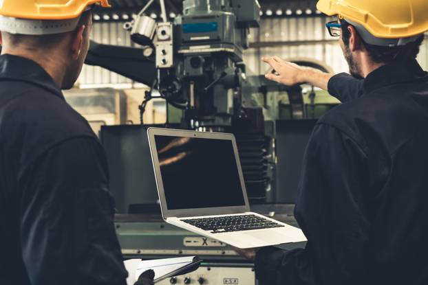 Skillful factory worker working with laptop computer to do procedure checklist .