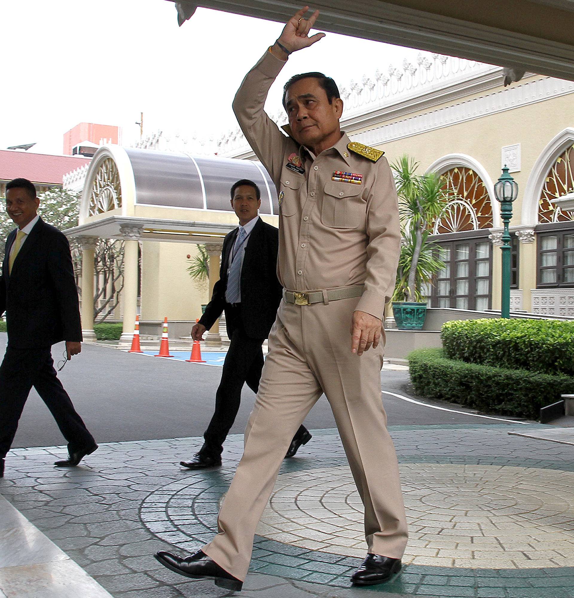 Thailand's Prime Minster Prayuth Chan-ocha waves to reporters next to a cardboard cut-out of himself at the government house in Bangkok