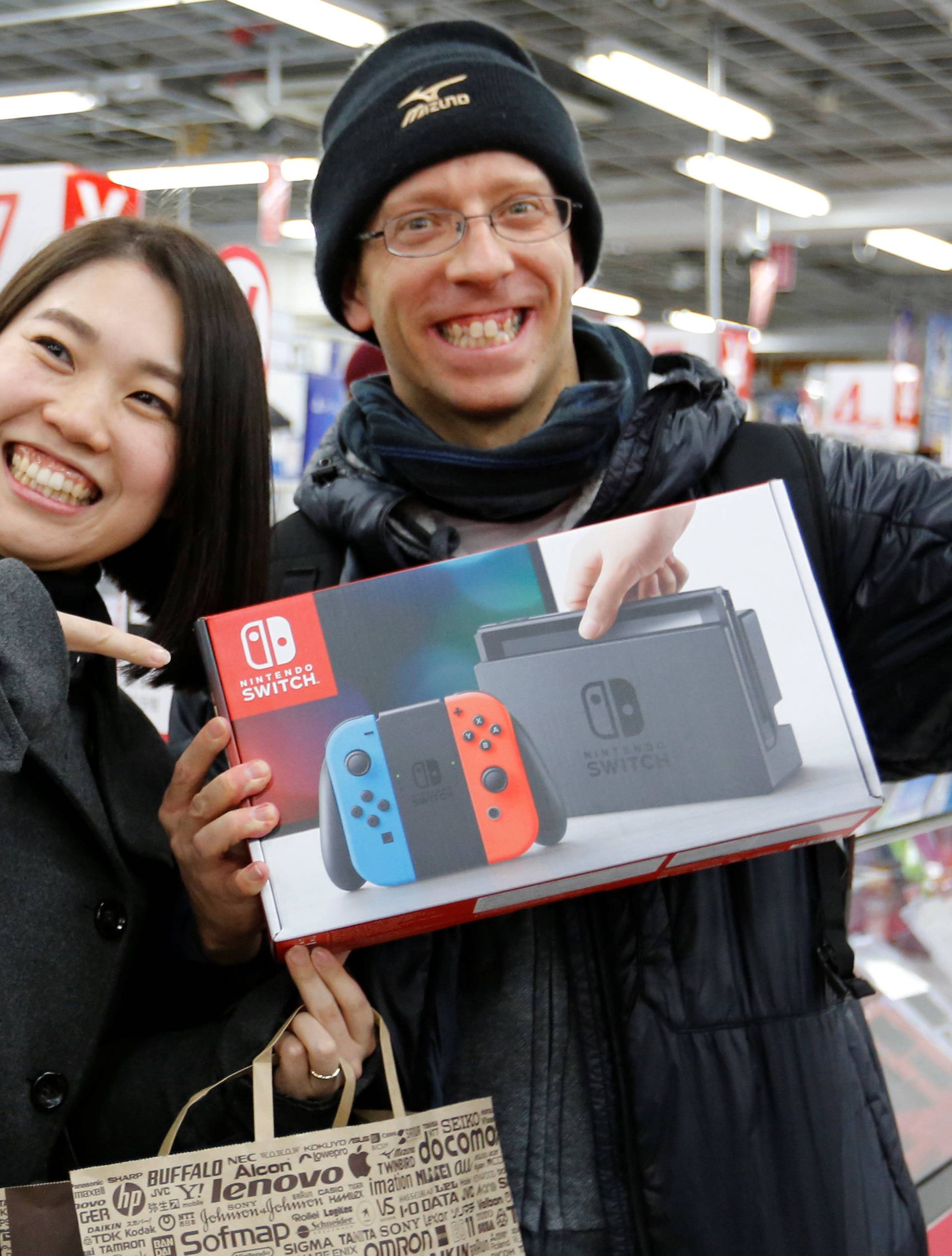 Nao Imoto and her husband David Flores poses with their Nintendo Switch game console after buying it at an electronics store in Tokyo