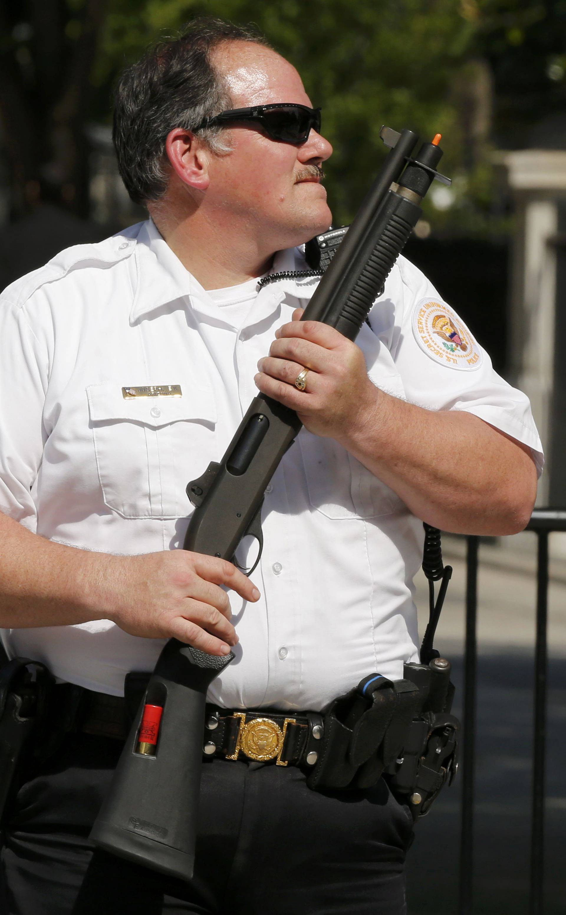 A uniformed Secret Service agent holds a shotgun after a shooting incident near the White House in Washington DC