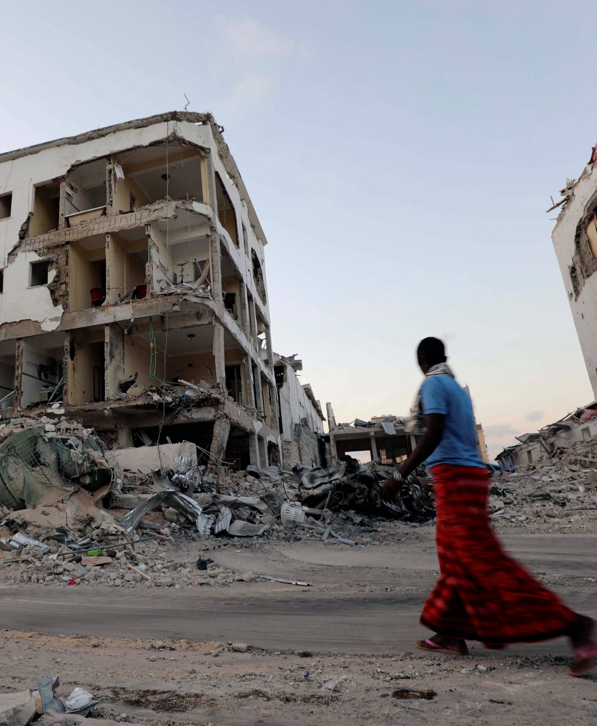 A man walks near damaged buildings after a suicide car bomb exploded, targeting a hotel in a business center in Maka Al Mukaram street, Mogadishu