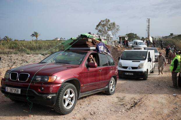 Displaced people cross the bridge linking southern Lebanon to the rest of the country, which was hit earlier in an Israeli strike, in Qasmiyeh