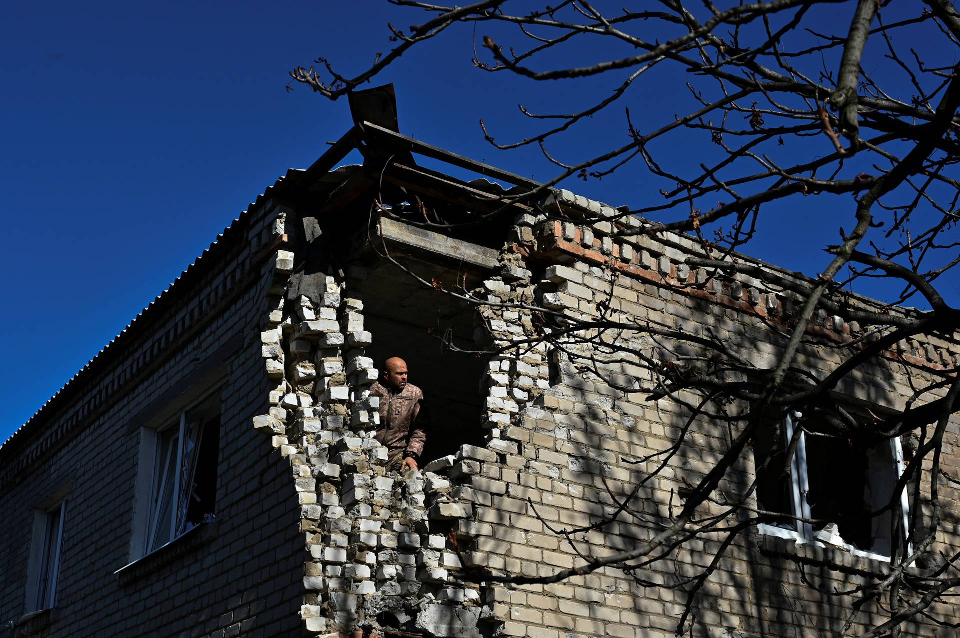 Ukrainian serviceman inspects a damaged residential building in the village of Velyka Novosilka