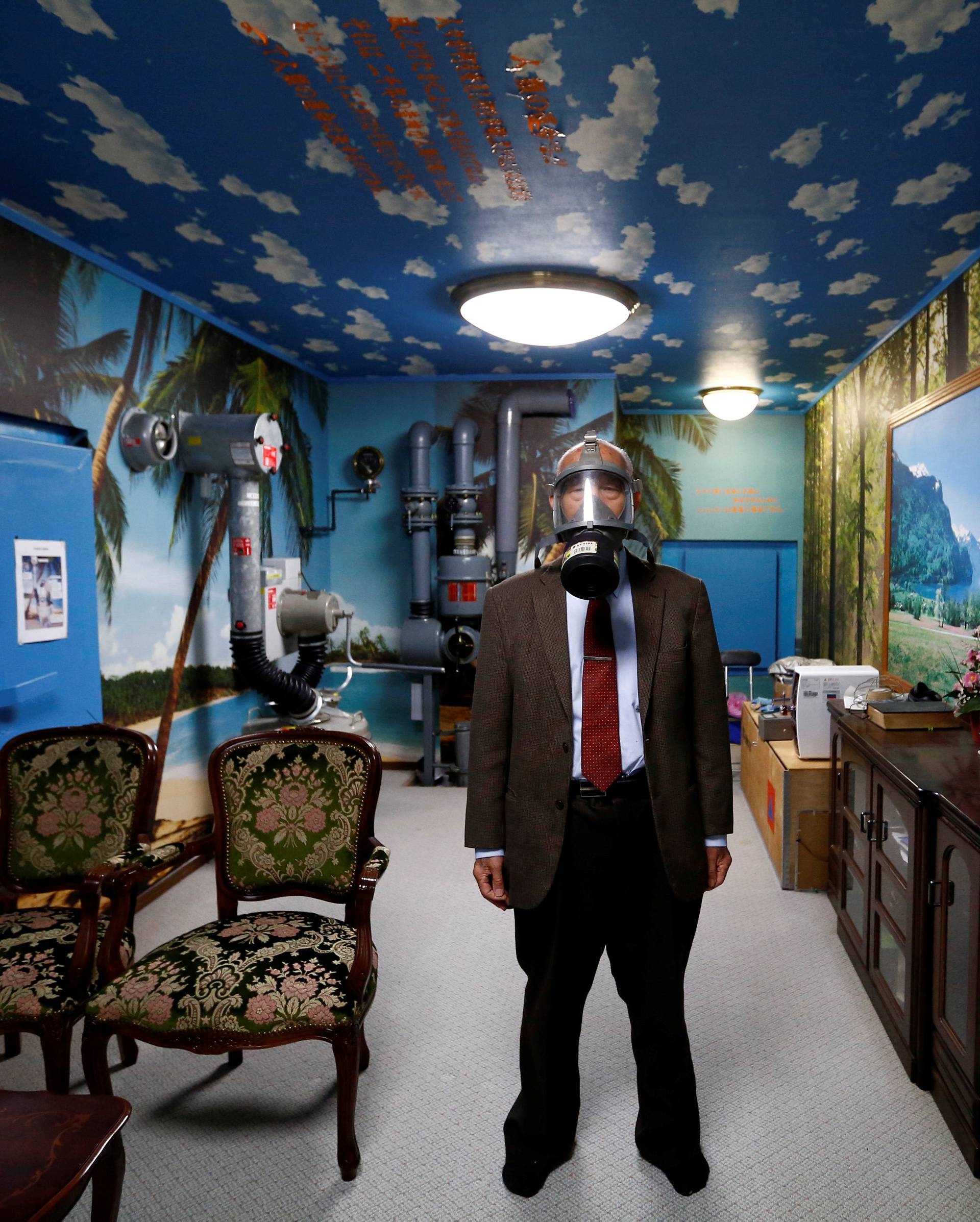Seiichiro Nishimoto, CEO of Shelter Co., poses wearing a gas mask at a model room for the company's nuclear shelters in the basement of his house in Osaka