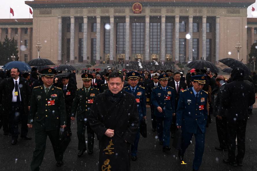 Military delegates leave the Great Hall of the People amid snowfall on Tiananmen Square before the opening sessions of the annual CPPCC