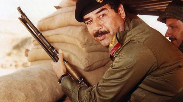 Iraq: Saddam Hussein, President of Iraq 1979-2003, posing with a rifle in a dugout during the Iran-Iraq War (1980-1988) <br/><br/>