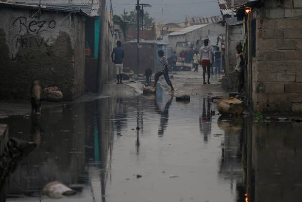 People walk on a flooded street after Hurricane Matthew passes Cite-Soleil in Port-au-Prince