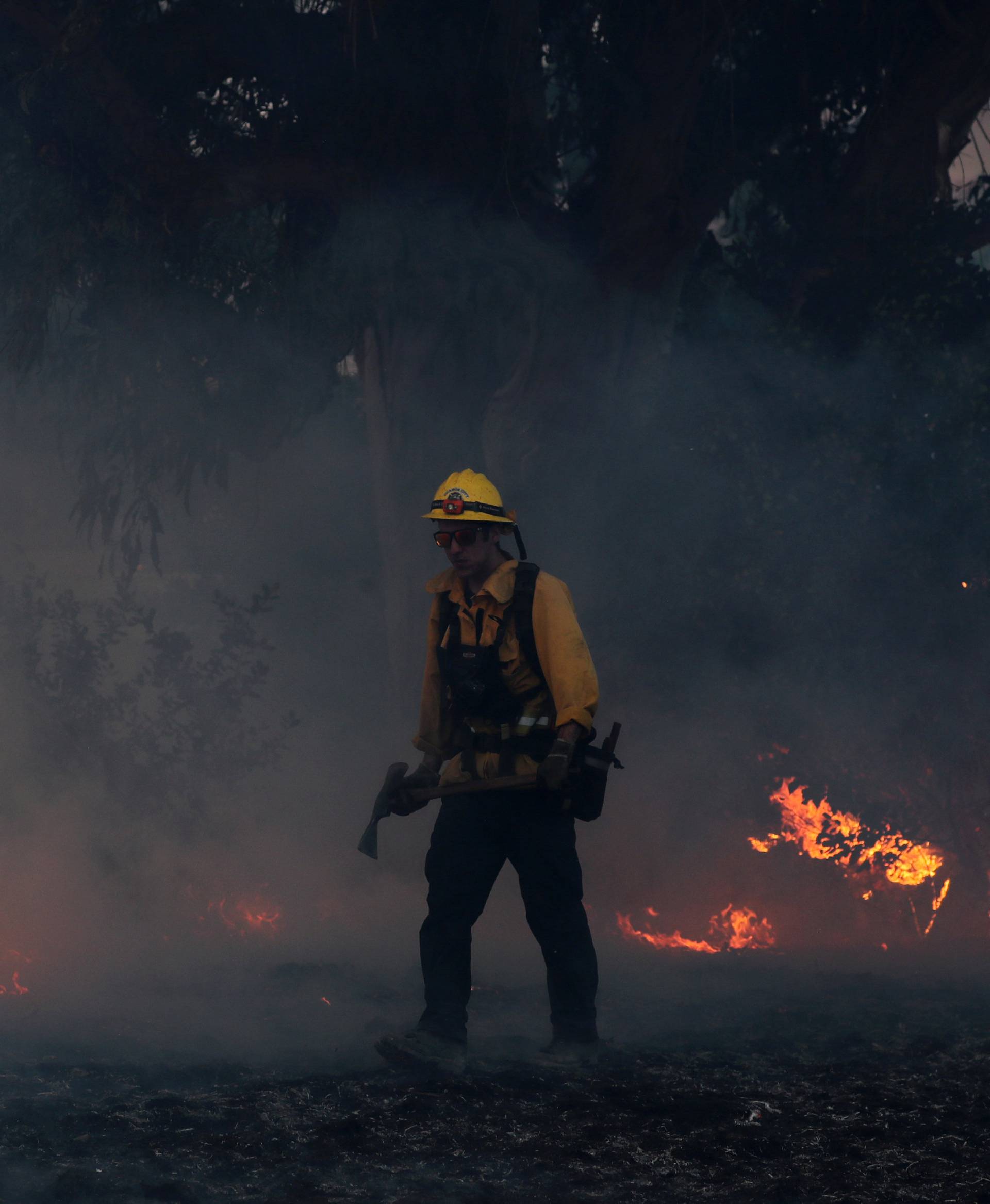 A firefighter works to put out hot spots on a fast moving wind driven wildfire in Orange, California