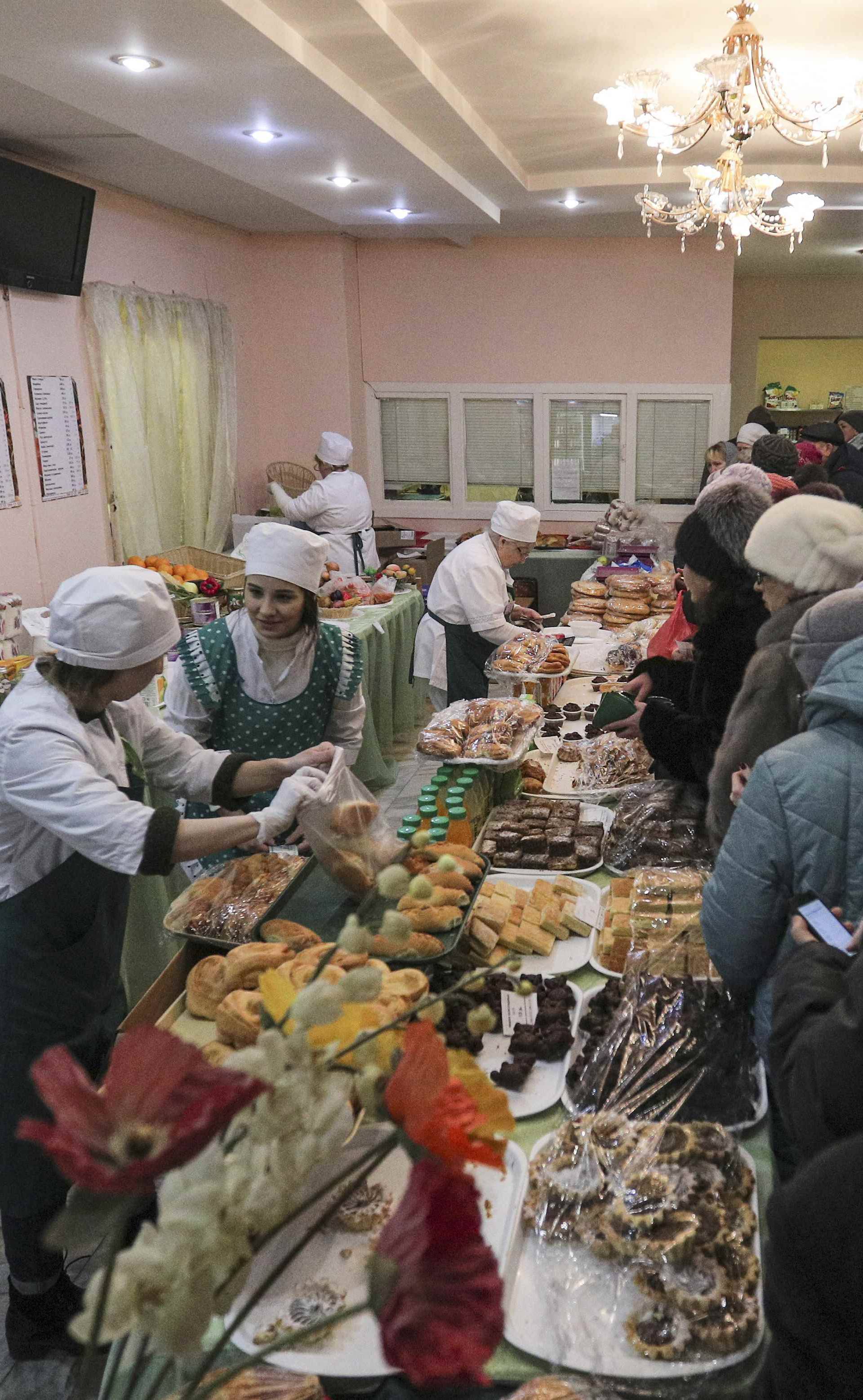 People queue before buying snacks at a polling station during the presidential election in Kazan