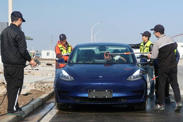 Employees clean a China-made Tesla Model 3 vehicle at the Shanghai Gigafactory of the U.S. electric car maker in Shanghai