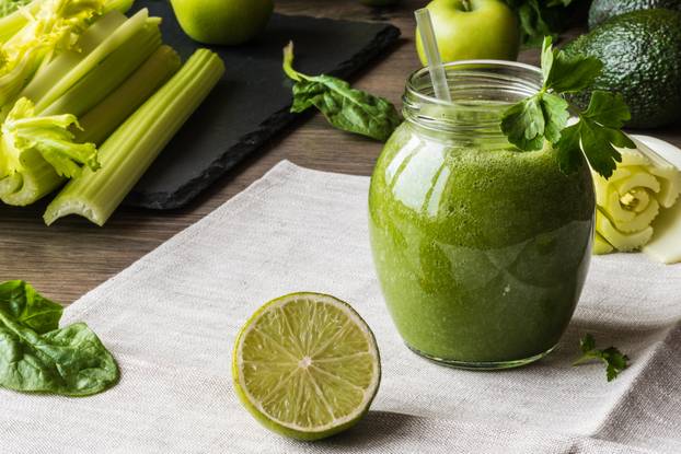 Detox diet. Green smoothie with different vegetables on wooden background