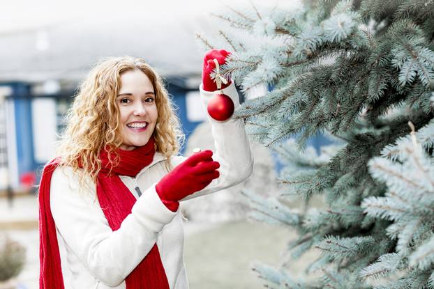 Woman decorating Christmas tree outside