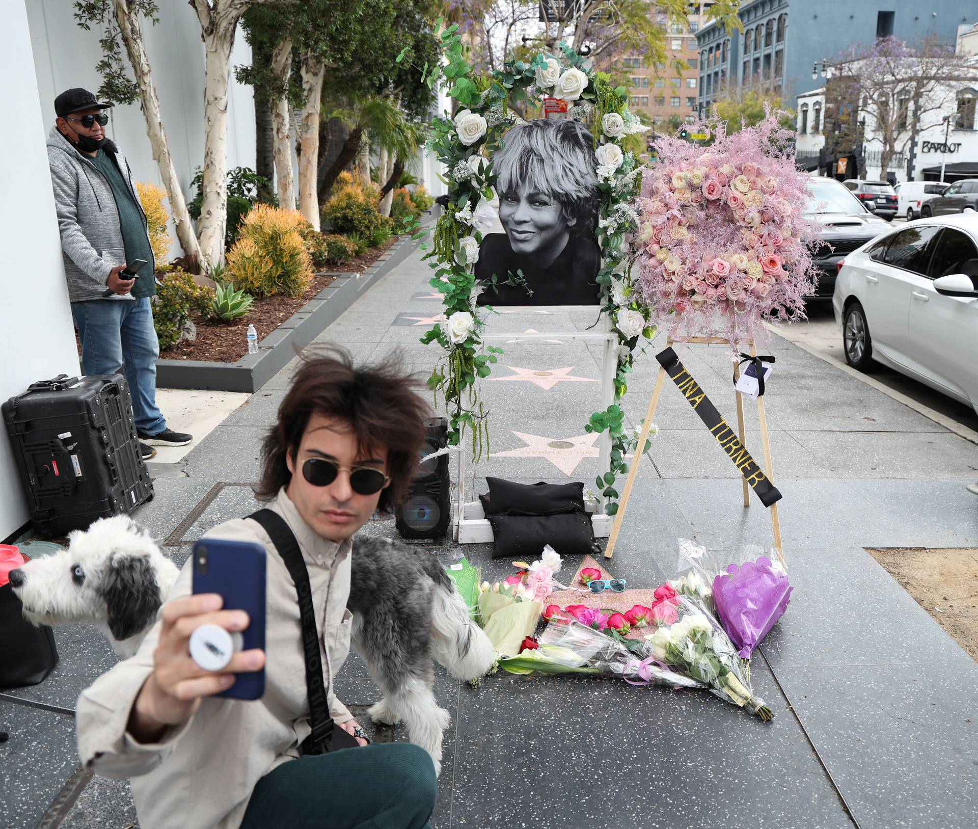 A person takes a selfie next to the star of late singer Tina Turner which is adorned with flowers on the Hollywood Walk of Fame in Los Angeles