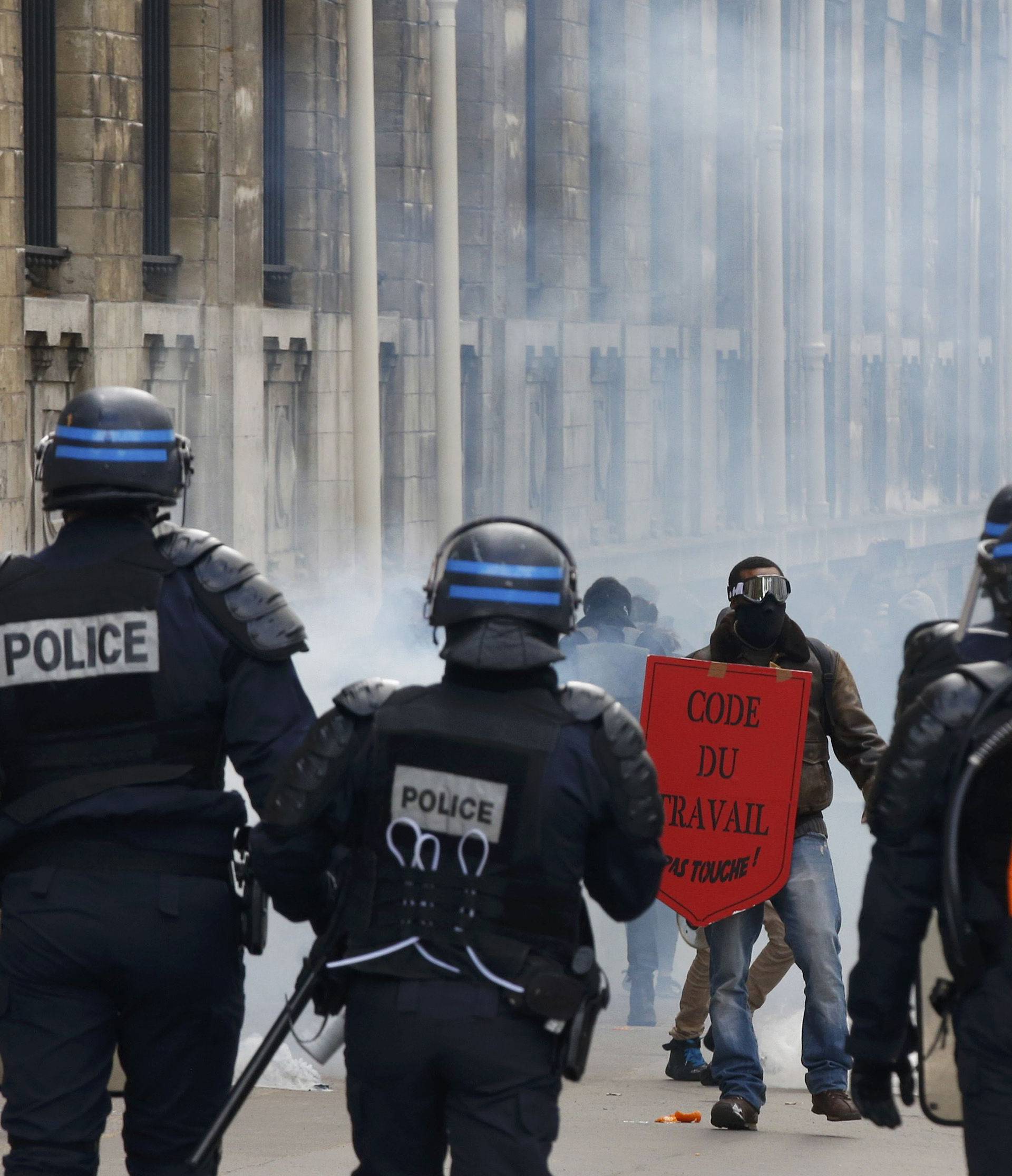 Masked youths face off with French riot police attend a demonstration against the French labour law proposal in Paris
