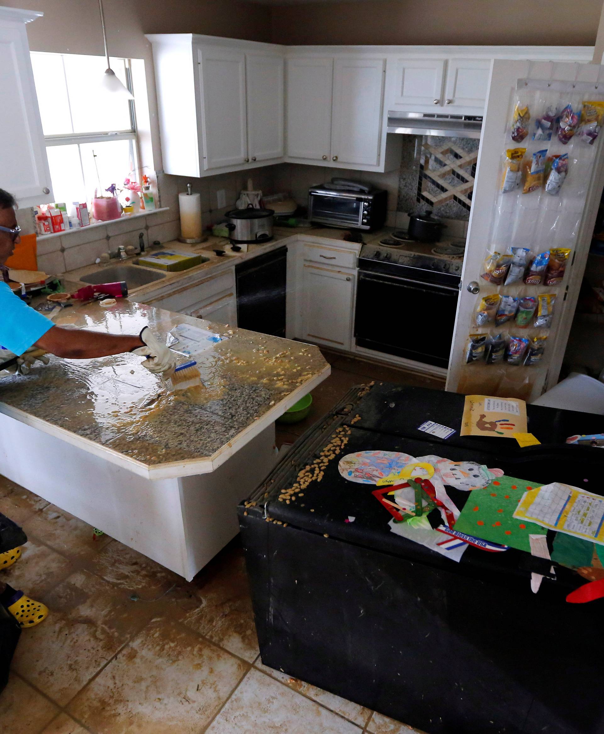 Milton Seecoomar, father of homeowner Vanessa Bailey, cleans a flood damaged kitchen in Denham Springs