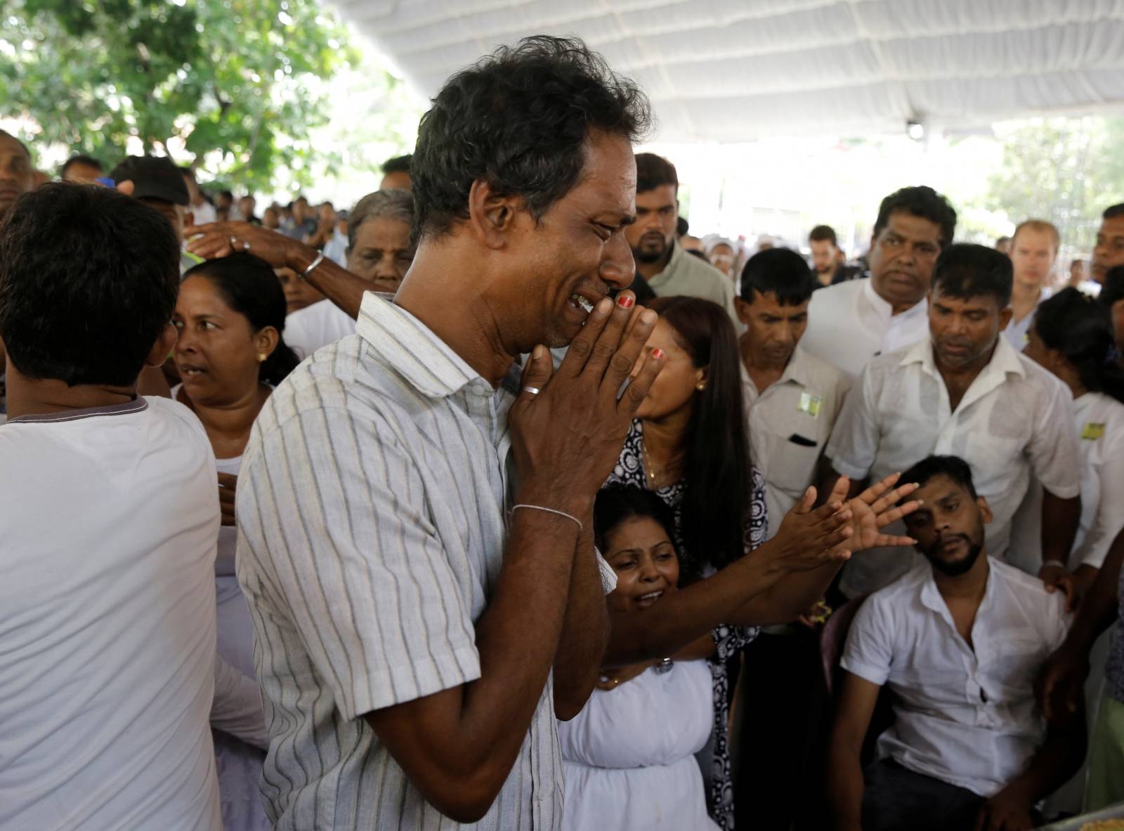 People react near a casket during a mass for victims, two days after a string of suicide bomb attacks on churches and luxury hotels across the island on Easter Sunday, in Negombo