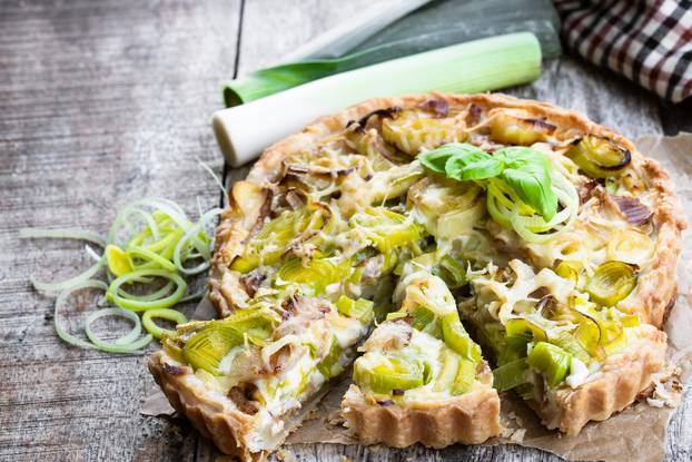 Leek tart with bacon and cheese on wooden table 