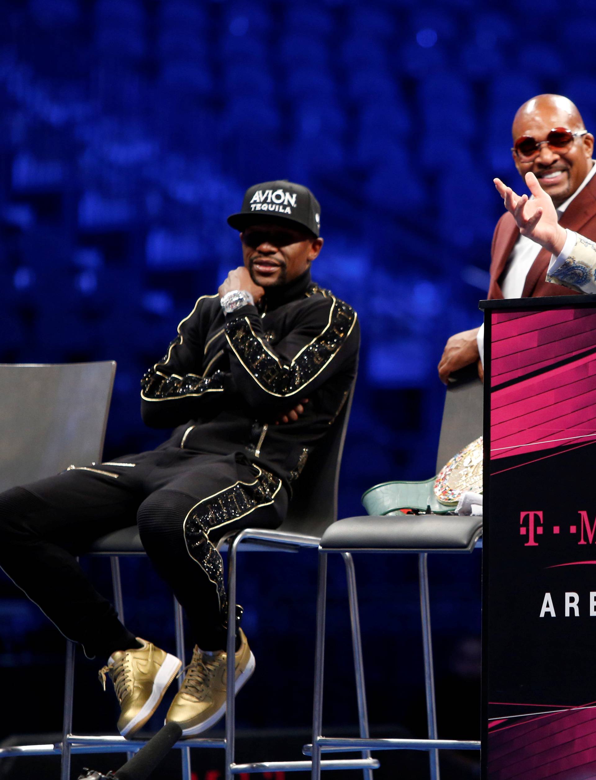 UFC lightweight champion Conor McGregor of Ireland responds to a question during post-fight news conference with undefeated boxer Floyd Mayweather Jr. (L) of the U.S. and Mayweather advisor Leonard Ellerbe at T-Mobile Arena in Las Vegas