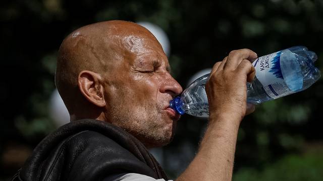A man drinks water on the street during an abnormally hot summer day in central Kyiv