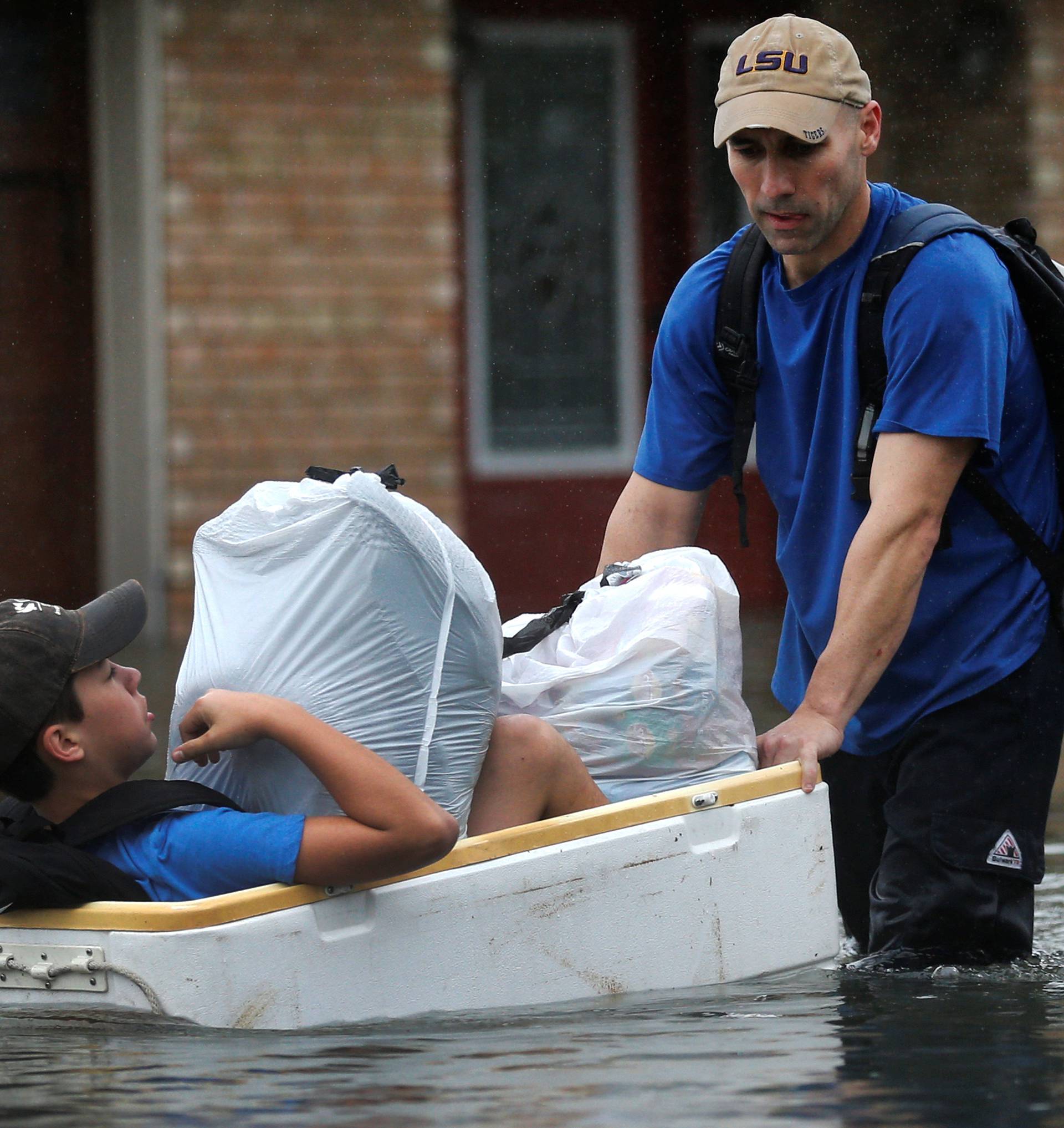 Tim Linscomb carries his 12-year-old son Colby as he wades through flood waters from Tropical Storm Harvey in Orange