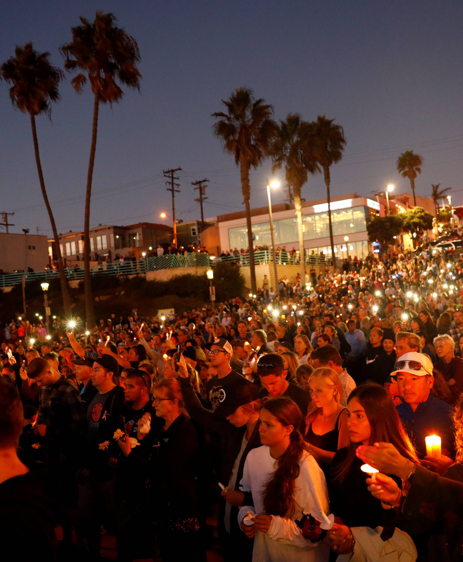 People hold candles and flashlights into the air during a memorial for Rachael Parker and Sandy Casey, Manhattan Beach city employees and victims of the October 1st Las Vegas Route 91 music festival mass shooting