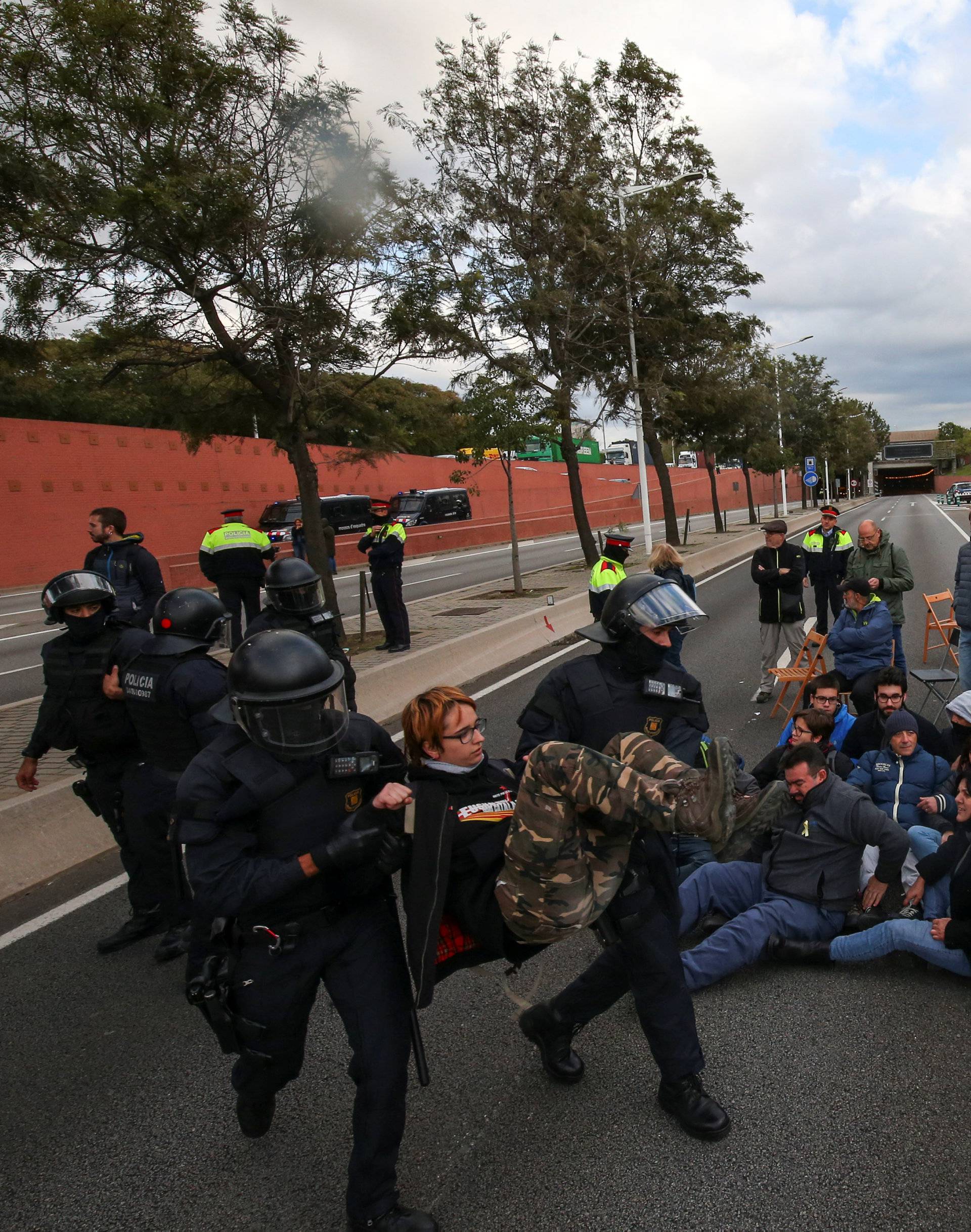 Police remove a protestor who was part of a group of protestors blocking a ring road in Barcelona during a partial regional strike in Barcelona