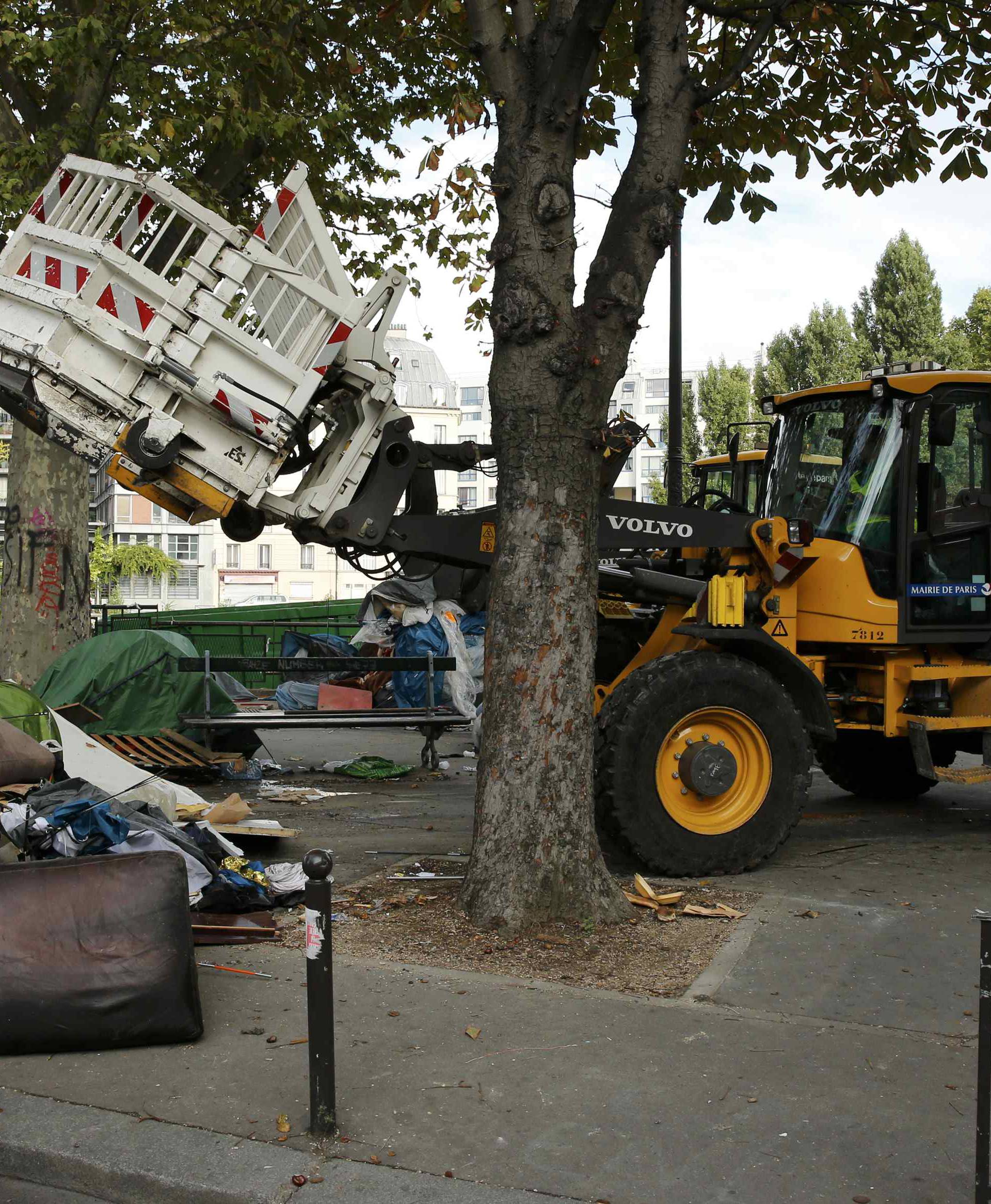 City workers remove tents and mattresses from an evacuated makeshift migrant camp near the metro stations of Jaures and Stalingrad in Paris