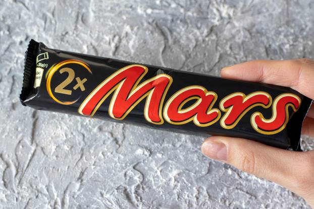 IRPEN, UKRAINE, DECEMBER 2 20222, Mars chocolate bar in the hand of a woman on a gray background, Illustrative Editorial.