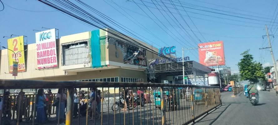People stand near a damaged building after an earthquake, in General Santos City