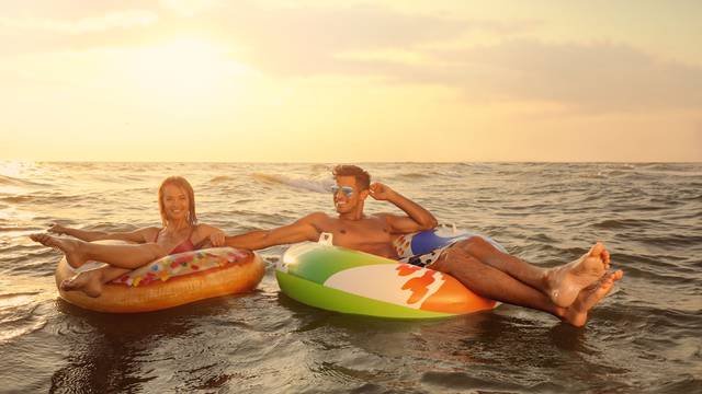 Happy,Couple,With,Inflatable,Rings,In,Sea