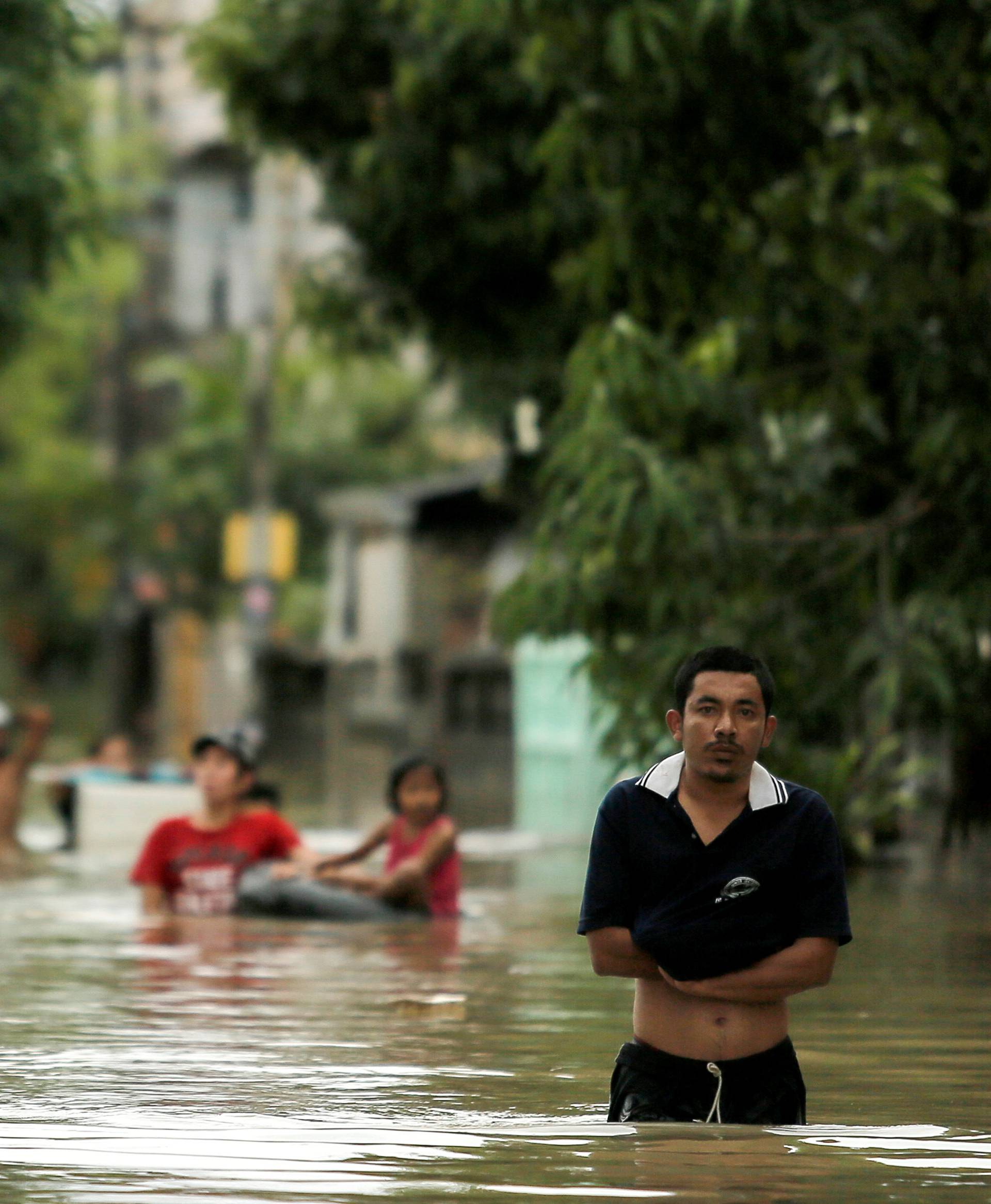 People walk in a flooded street at Muang district in Nakhon Si Thammarat province