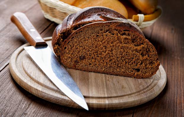 The cut black bread on a wooden table