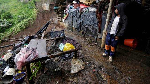 A child shields from the rain as he stands near his house damaged after a mudslide following heavy showers caused by the passing of Tropical Storm Earl, in the town of Huauchinango