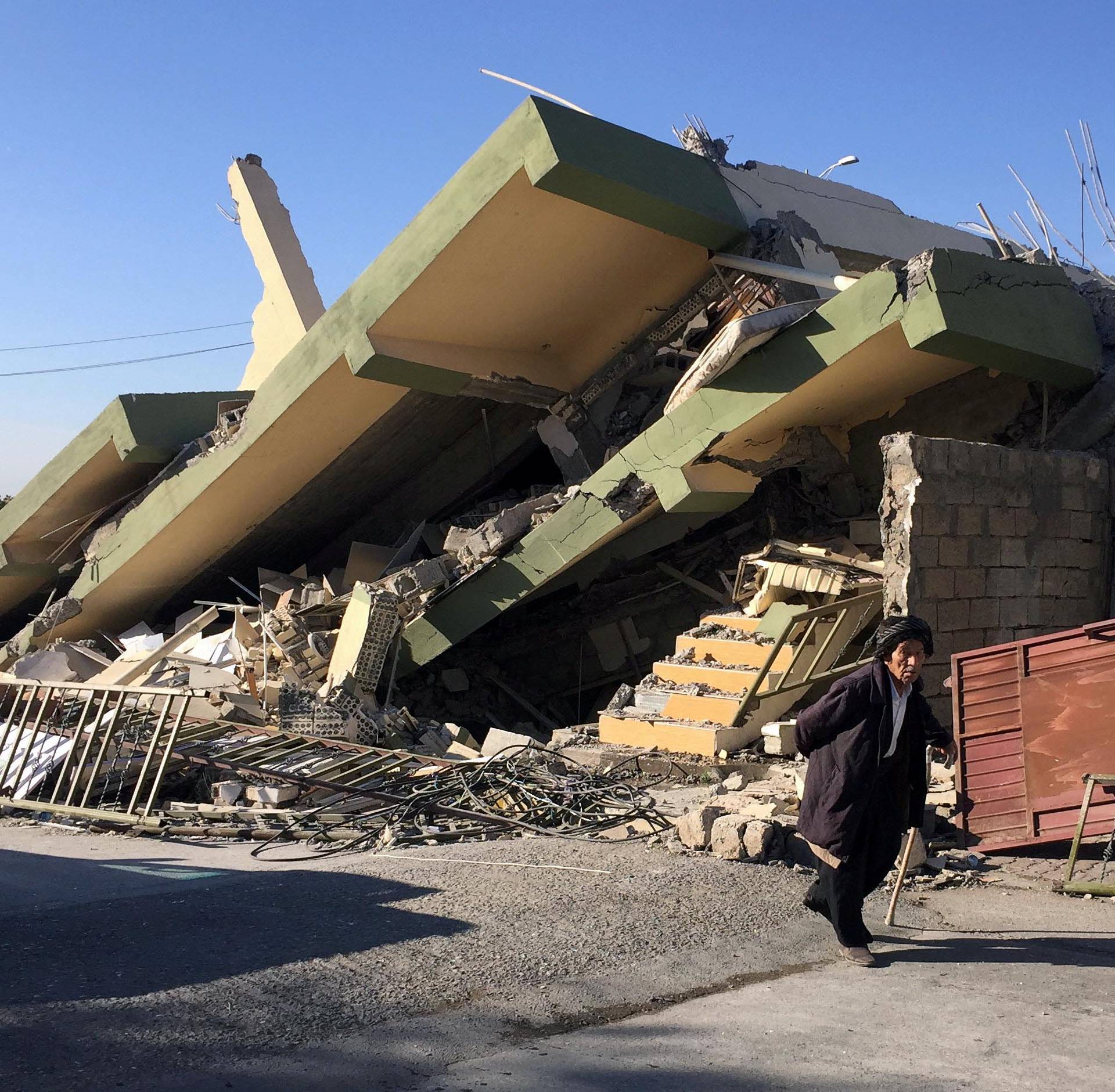 A man walks past a damaged building following an earthquake in Darbandikhan
