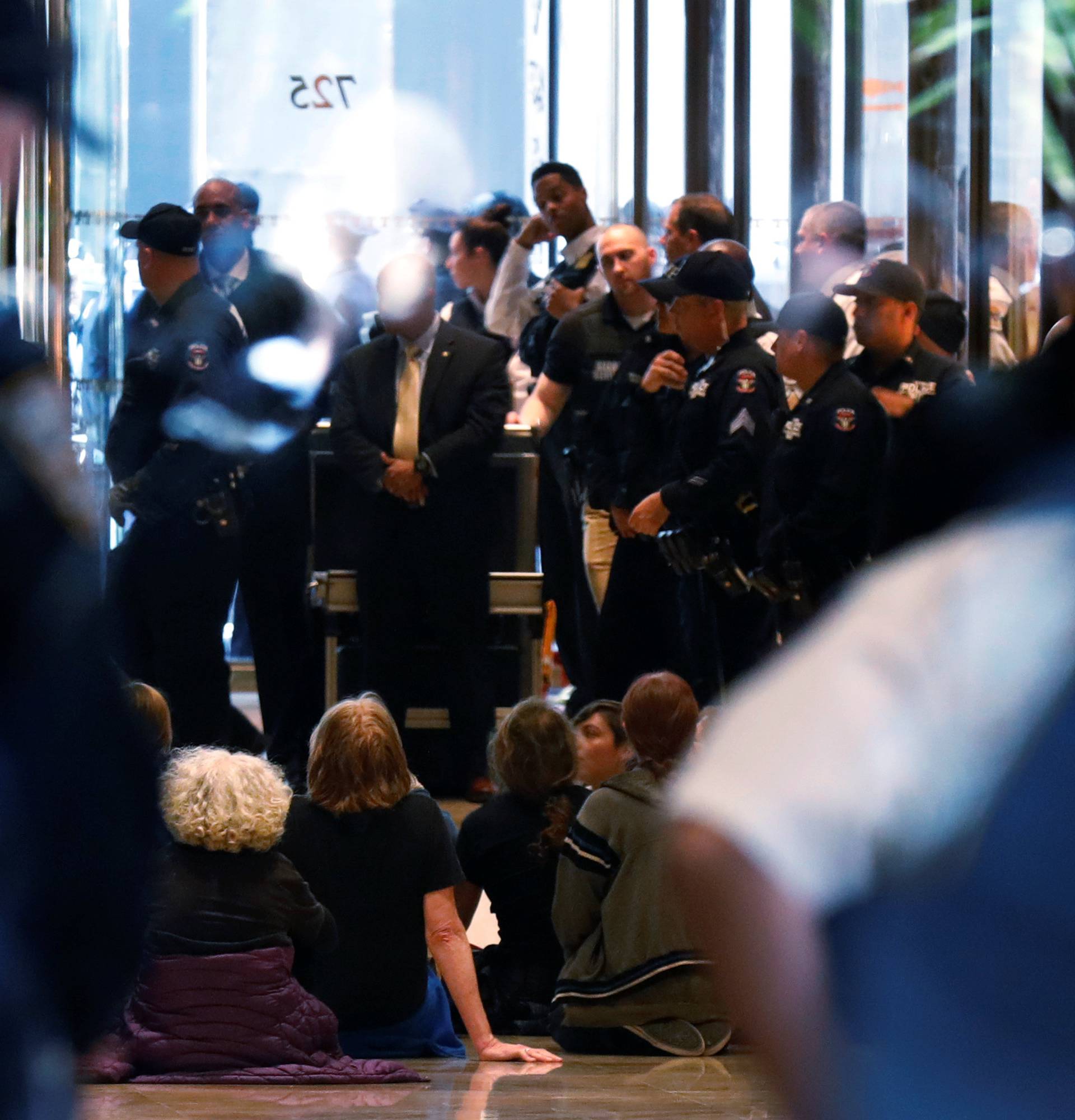 Protestors sit down in the lobby of Trump Tower as New York City Police officers (NYPD) prepare to make arrests in New York City