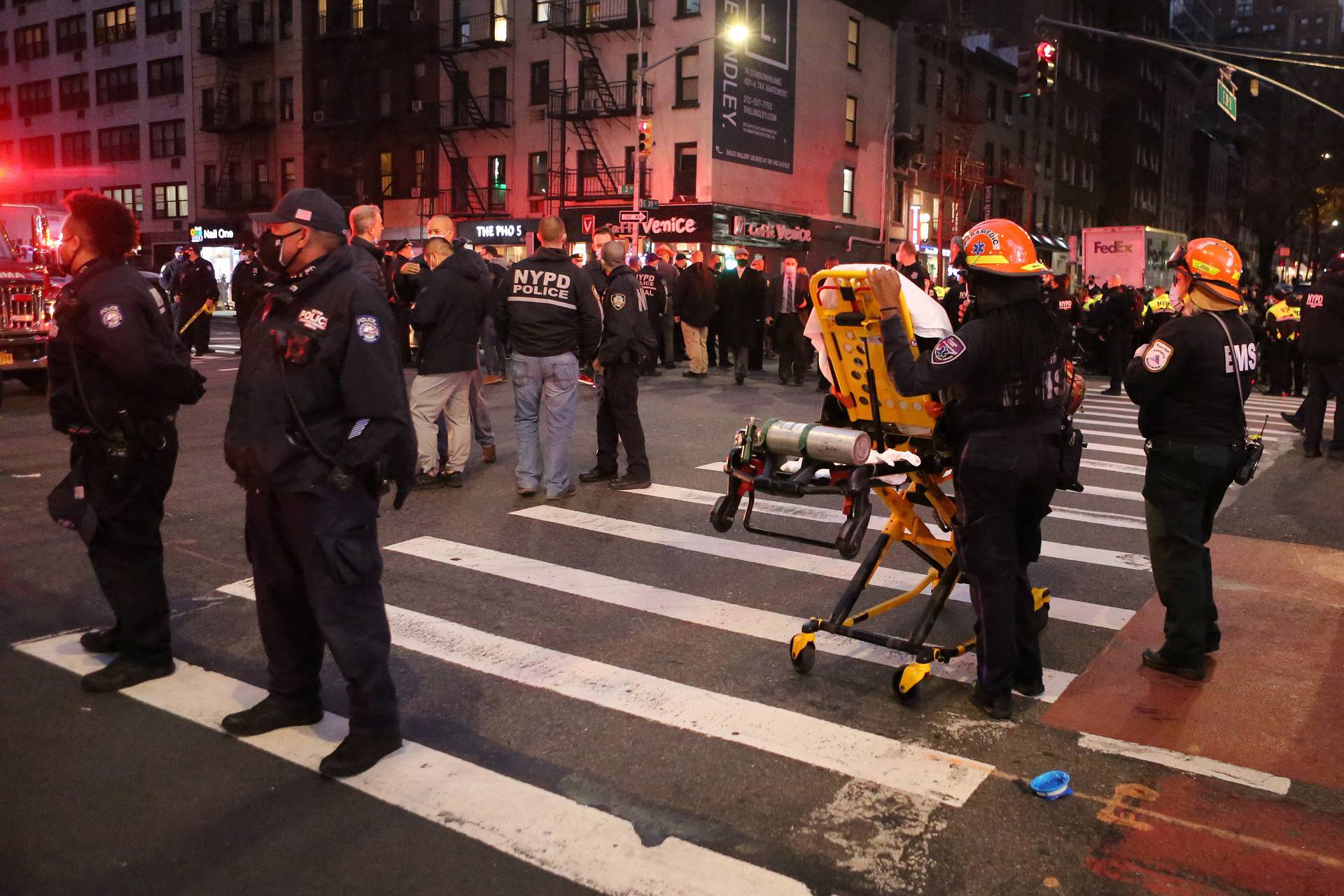 Police and EMS stand in the street at the location of a vehicle that struck multiple pedestrians on Third Avenue