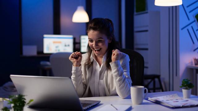 Happy businesswoman reading great online news on laptop