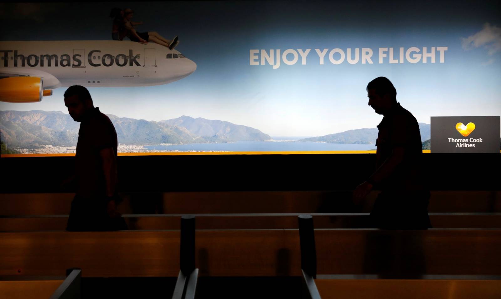 Men walk past a Thomas Cook banner at Dalaman Airport