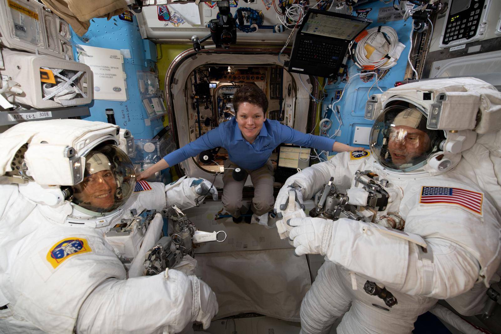 Astronaut Anne McClain assists fellow astronauts Christina Koch and Nick Hague ahead of a set of upcoming spacewalks at the International Space Station