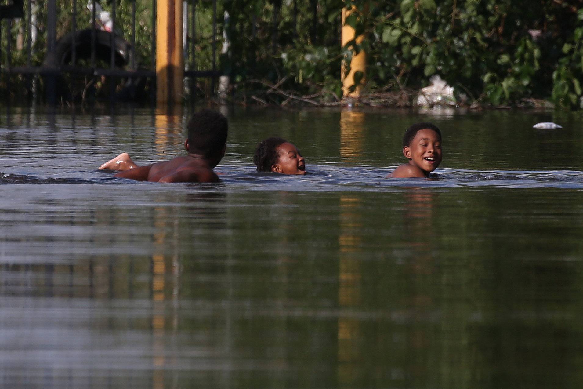 Children play in flood water in an apartment parking lot as a result of Tropical Storm Harvey in Port Arthur, Texas