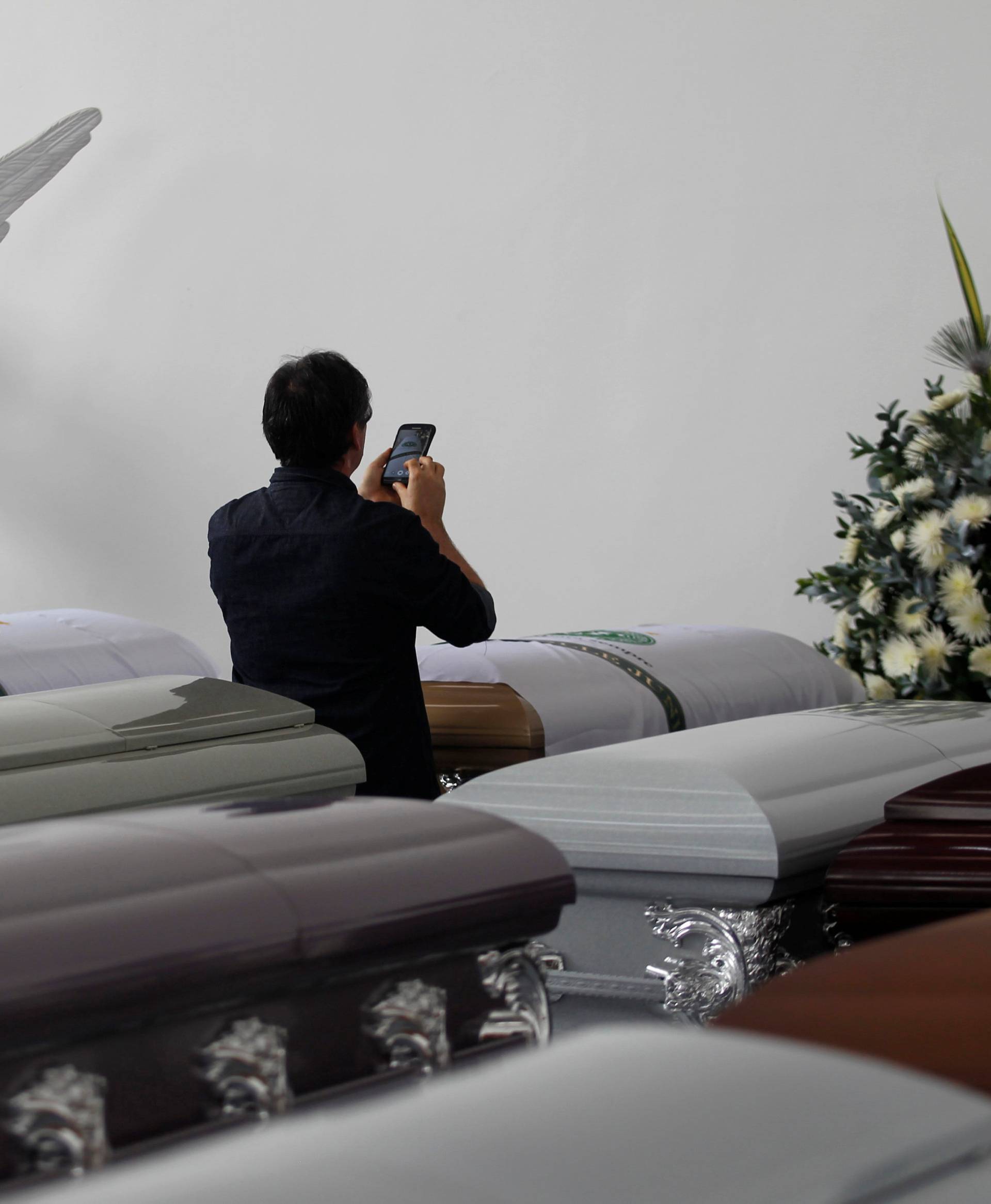 A relative takes a photograph of the coffin of a victim who died along with others in an accident of the plane that crashed into the Colombian jungle with the Brazilian soccer team onboard, in Medellin