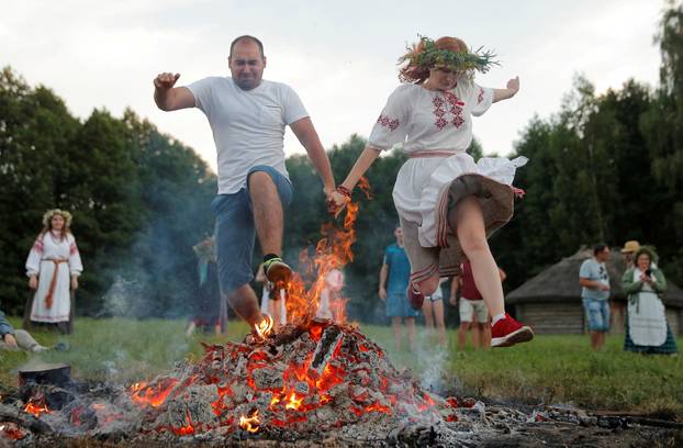 People jump over a campfire as they take part in the Ivan Kupala festival near the village Aziarco