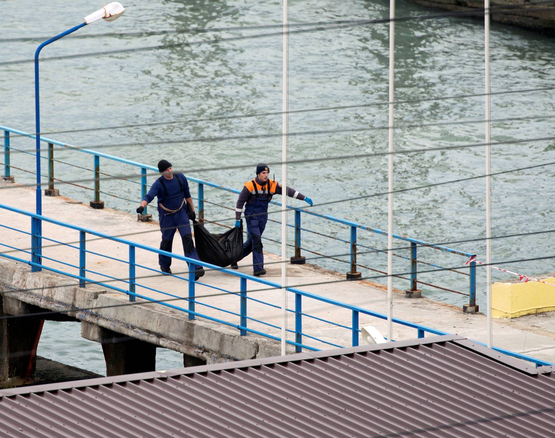 Russian Emergencies Ministry members carry plastic bag at quay of Black Sea in Sochi suburb of Khosta