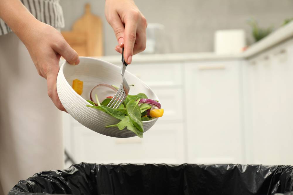 Woman,Throwing,Vegetable,Salad,Into,Bin,Indoors,,Closeup