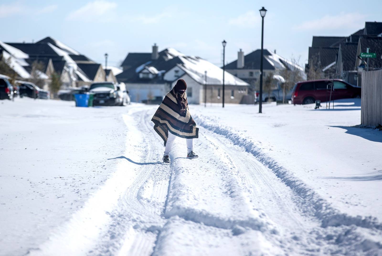 A man walks to his friend's home in a neighbourhood without electricity as snow covers the BlackHawk neighborhood in Pflugerville