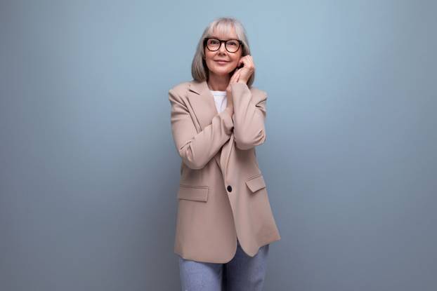 portrait of a nice-looking old woman in a youthful look on a studio background with copy space