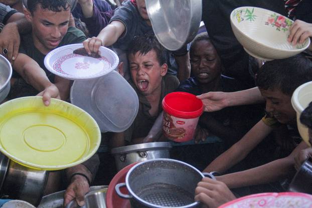 FILE PHOTO: Palestinians gather to receive food cooked by a charity kitchen, amid the Israel-Hamas conflict, in the northern Gaza Strip