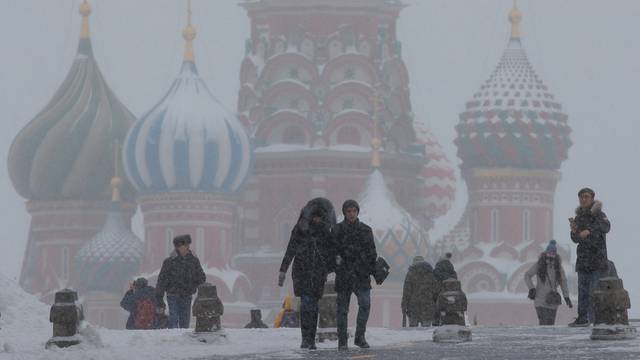 People walk in the Red Square during heavy snowfall in Moscow