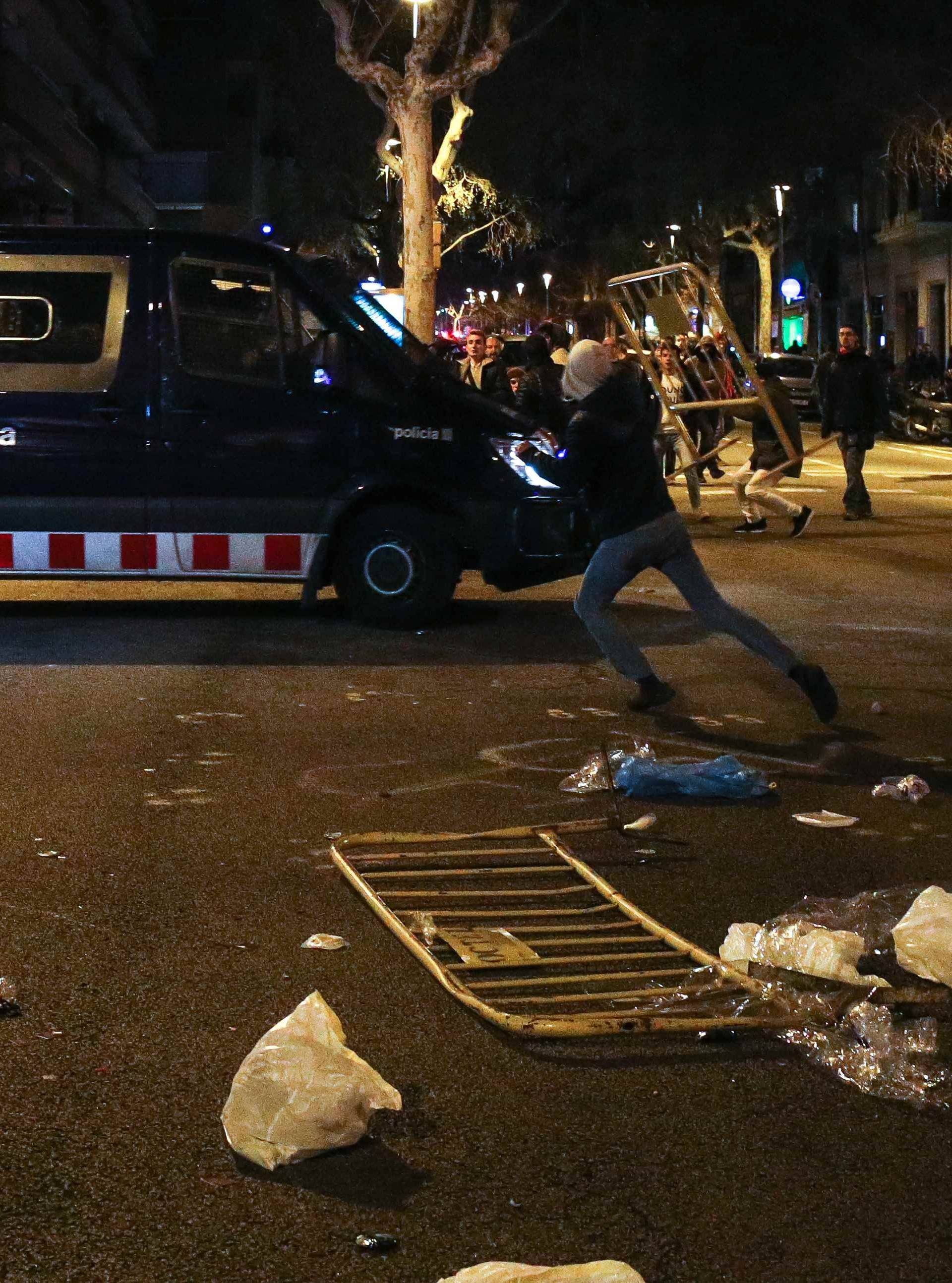 A protestor throws a barrier at a Catalan police van during skirmishes after former regional president Carles Puigdemont was detained in Germany,  in Barcelona