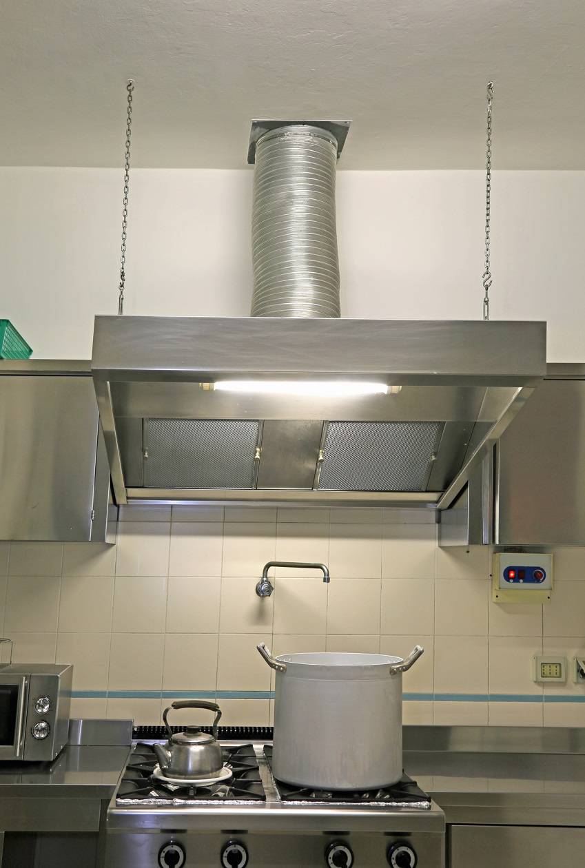 hood of the industrial kitchen with a metal pot on the stove and